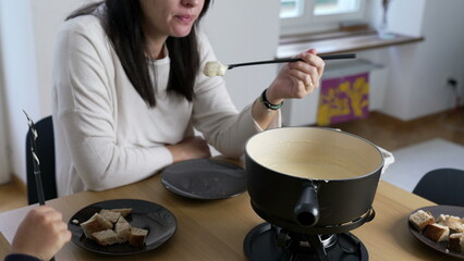Swiss Fondue Feast, woman Enjoying Bread and Cheese at Home. homemade traditional European dish in Switzerland