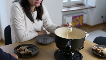 Swiss Fondue Feast, woman Enjoying Bread and Cheese at Home. homemade traditional European dish in Switzerland