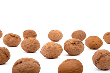 Scattered whole walnuts lie on a white background. Backgrounds and textures. Isolate.