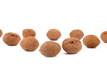 Scattered whole walnuts lie on a white background. Backgrounds and textures. Isolate.