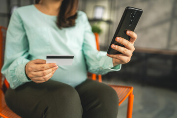 Pregnant woman doing online shopping hold credit card sit at home