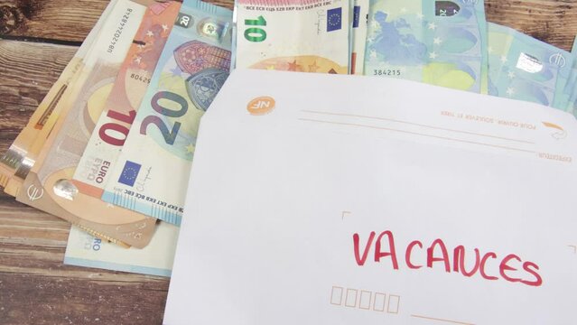enveloppe rempli de billets de banque avec un papier avec &eacute;crit dessus "vacances" en fran&ccedil;ais