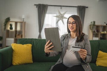 Pregnant woman doing online shopping hold credit card sit at home