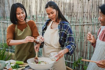 Happy asian mother and adult daughter cooking traditional thai rice at house terrace