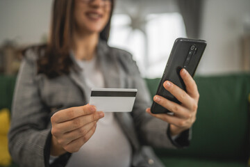Pregnant woman doing online shopping hold credit card sit at home