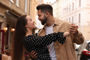 Lovely couple dancing together on city street