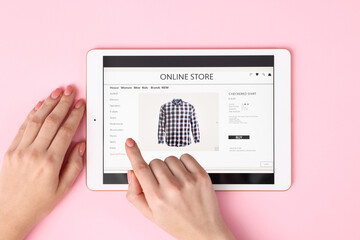 Woman with tablet shopping online on pink background, top view