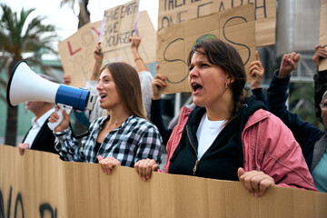Close up Angry and rebellious woman speaking and protesting with megaphone at demonstration at...