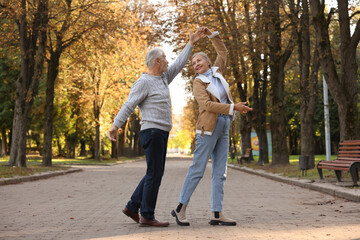 Affectionate senior couple dancing together in autumn park