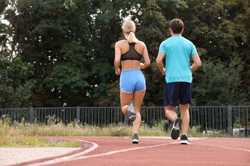 Obraz premium Healthy lifestyle. Sporty couple running at stadium, back view