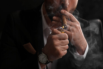 Man lightning cigar on black background, closeup