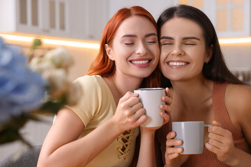 Portrait of happy young friends with cups of drink at home