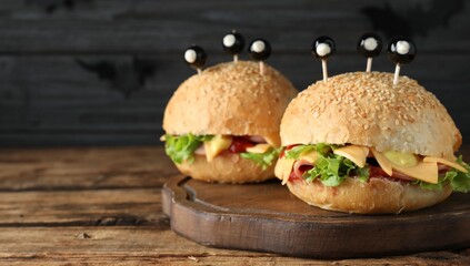 Cute monster burgers served on wooden table, space for text. Halloween party food