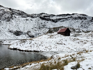 mountain hut in the snow. froze mountain, lake and hut. valley on the mountain peaks in Carpathian,...