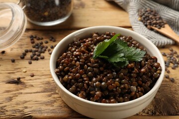 Delicious lentils with parsley in bowl on wooden table, closeup. Space for text