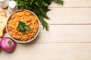 Delicious red lentils with parsley in bowl served on wooden table, flat lay. Space for text