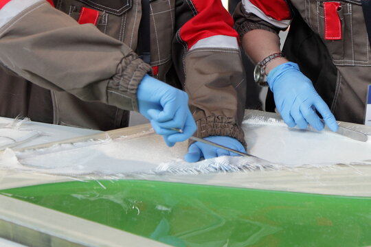 Industrial plant employees cut and put fiberglass into a matrix for infusion with epoxy resin in the production of fiberglass products