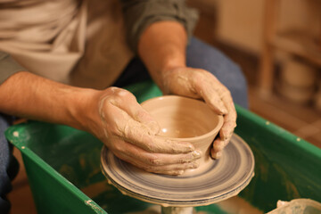 Clay crafting. Man making bowl on potter's wheel indoors, closeup