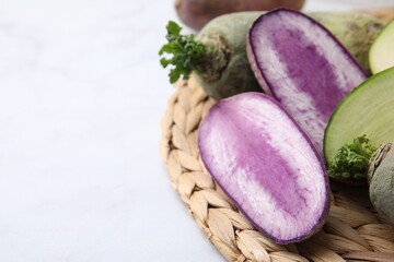 Green and purple daikon radishes on white table, closeup. Space for text