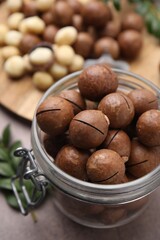 Tasty Macadamia nuts in jar on table, closeup