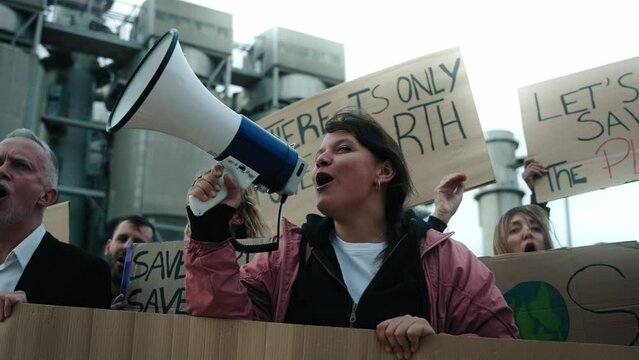 Woman shouting with a megaphone in a demonstration. Group of people at manifestation on climate change and global warming pollution and factories, environmentalists involved in the fight against