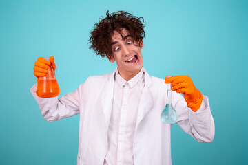 A funny doctor conducts chemical experiments with liquids. A man with test tubes. The study of the interactions of substances. Blue background.