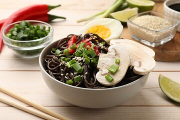 Tasty buckwheat noodles (soba) with mushrooms, egg and chili pepper served on wooden table, closeup