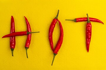 Red hot chilli peppers spelling the word hot. Red and spicy chili pepers creating a word hot on white background
