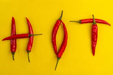 Fotobehang Red hot chilli peppers spelling the word hot. Red and spicy chili pepers creating a word hot on white background © svetograph