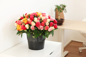 Bouquet of beautiful roses on white chest of drawers indoors, space for text