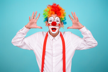 A joyful clown. A cute man in a suit and makeup for a holiday for children. A fool. Blue background. Copy the space.