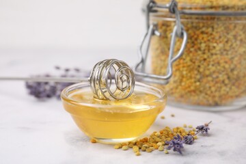 Fresh honey in bowl, dipper, bee pollen granules and lavender on light table, closeup