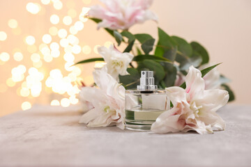 Obraz na płótnie Canvas Bottle of perfume and beautiful lily flowers on table against beige background with blurred lights, closeup