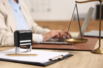 Notary using laptop at workplace in office, focus on stationery and scales of justice