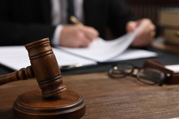 Lawyer working with documents at wooden table, focus on gavel