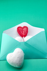 Blue envelope with a red lollipop inside with several hearts and a green background.