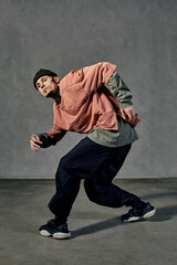 Handsome fellow with tattooed face, beard. Dressed in hat, colorful jumper, black pants and...