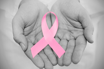Hand holding pink breast cancer awareness ribbon - Powered by Adobe