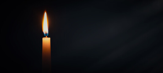 Fototapeta na wymiar Candle burning in darkness over black background