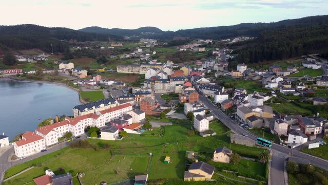 Beautiful aerial landscape in North of Spain, Galicia. Typically costal small village, surrounded by forest. Small bay of water. O Vicedo village. Drone slowly descending. 
