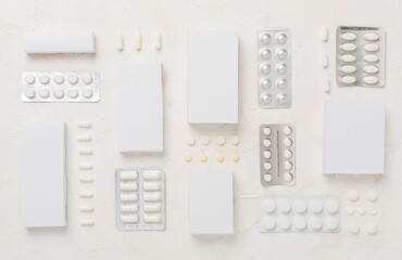 Different pills in blister packaging and boxes and on concrete background, top view