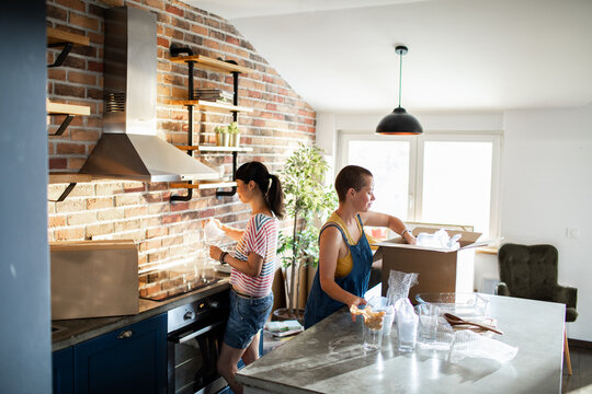Lesbian couple unpacking boxes and setting up their new kitchen
