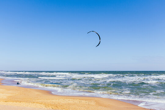 Kite surfing on the beach. Active lifestyle. Extreme sports concept. Man in wetsuit with kite board at seaside. Summertime active sport. Adrenaline and freedom. Surfer on aerial seascape background.