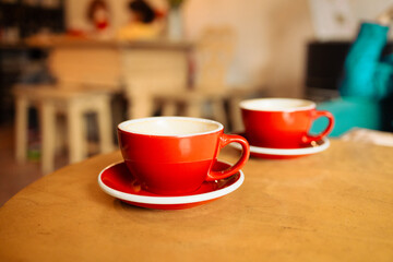 Two cups of cappuccino with latte art on wooden background. Beautiful foam, red ceramic cups. High quality photo 
