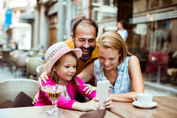 Family enjoying time together with smartphone at outdoor cafe