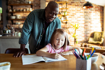 Grandfather helping granddaughter with homework in a cozy kitchen setting