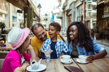 Multicultural family enjoying desserts at an outdoor cafe - obrazy, fototapety, plakaty