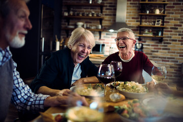 Senior friends sharing a meal and laughter at home