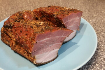 Two pieces of baked meat on a blue plate. Baked meat sprinkled with seasoning.