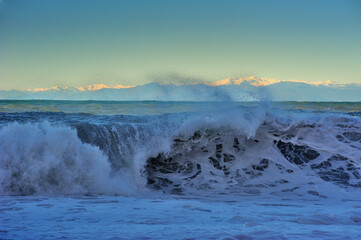 waves of the Mediterranean Sea rolling up and mountains in the distance on the horizon